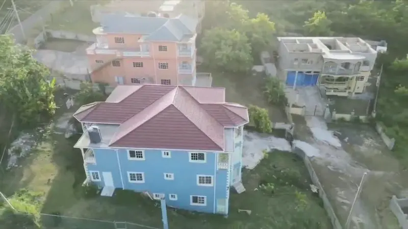 Aerial view of the house from the side, with neighbouring houses and trees around it