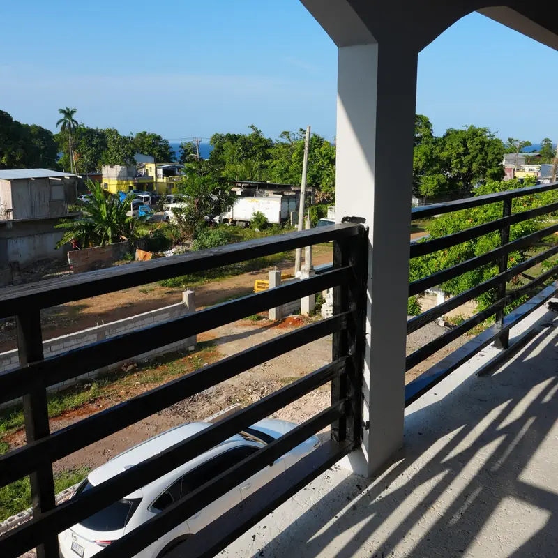 View from the upstairs balcony over trees and rooftops towards the sea