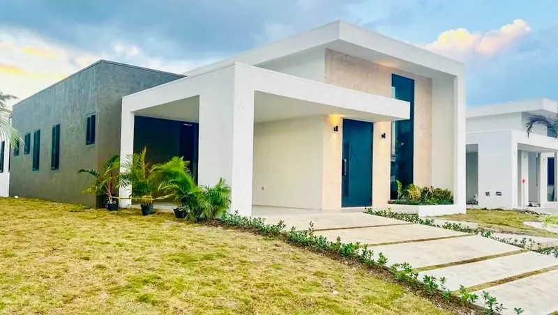 Palacio Rivera unit 219 from the front lawn: a white single-storey modern home with a dark front door and stone path